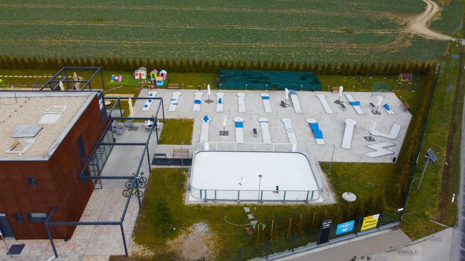 Ohradené biele klzisko vedľa minigolfových dráh, záber z dronu